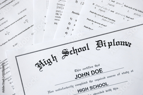 High School Diploma copy lies on many pages of alghebra and geometry tests and tasks. Graduation document photo