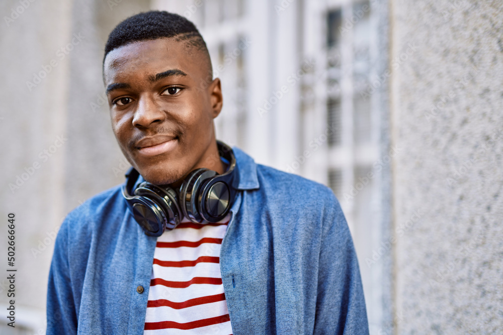 Obraz premium Young african american man smiling happy using headphones at the city.