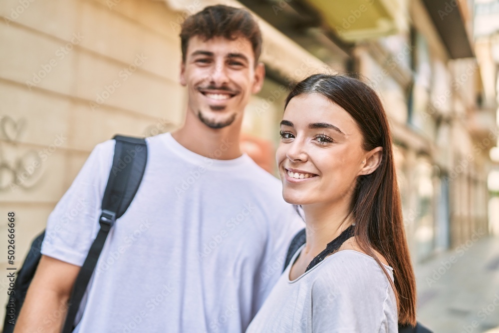 Man and woman couple wearing backpack hugging each other at street Man and woman couple wearing backpack hugging each other at street
