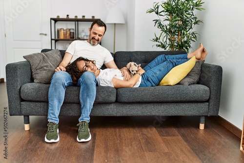Middle age hispanic couple relaxed sitting on the sofa with dog at home. © Krakenimages.com