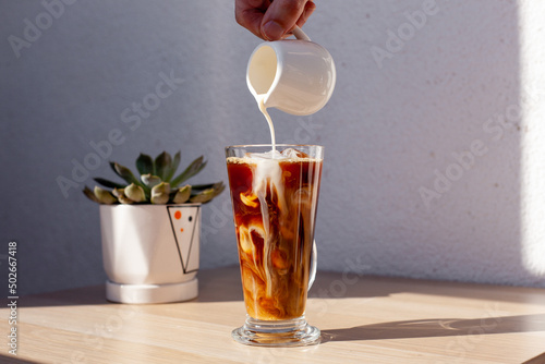 Tableau sur toile Ice coffee wooden table pouring milk creamer