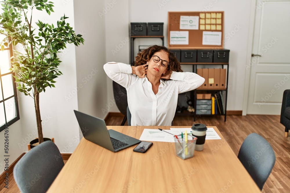 Middle age hispanic woman stretching and relaxing at office Middle age hispanic woman stretching and relaxing at office
