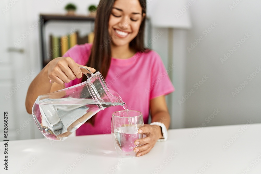 Young latin woman smiling confident pouring water at home Young latin woman smiling confident pouring water at home
