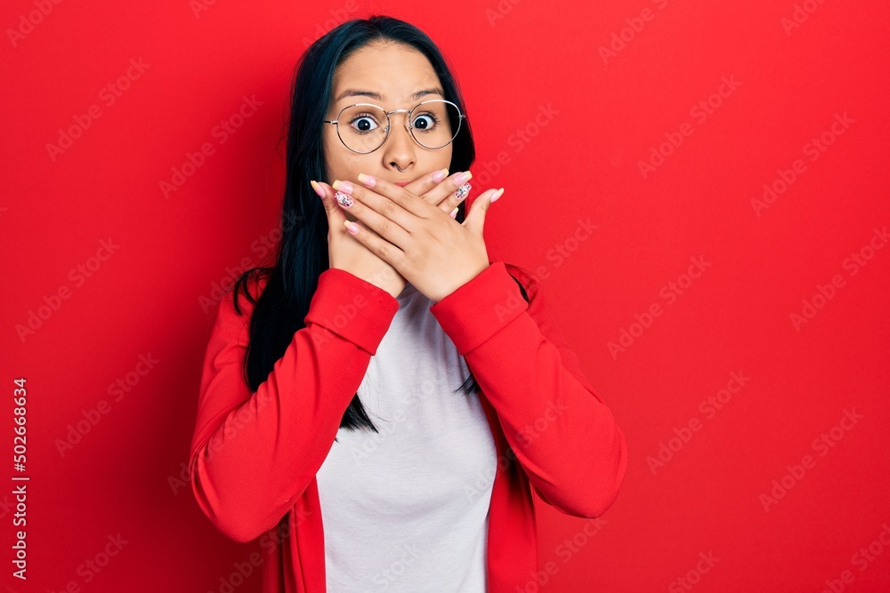 Beautiful hispanic woman with nose piercing wearing casual look and glasses shocked covering mouth with hands for mistake. secret concept. Beautiful hispanic woman with nose piercing wearing casual look and glasses shocked covering mouth with hands for mistake. secret concept.