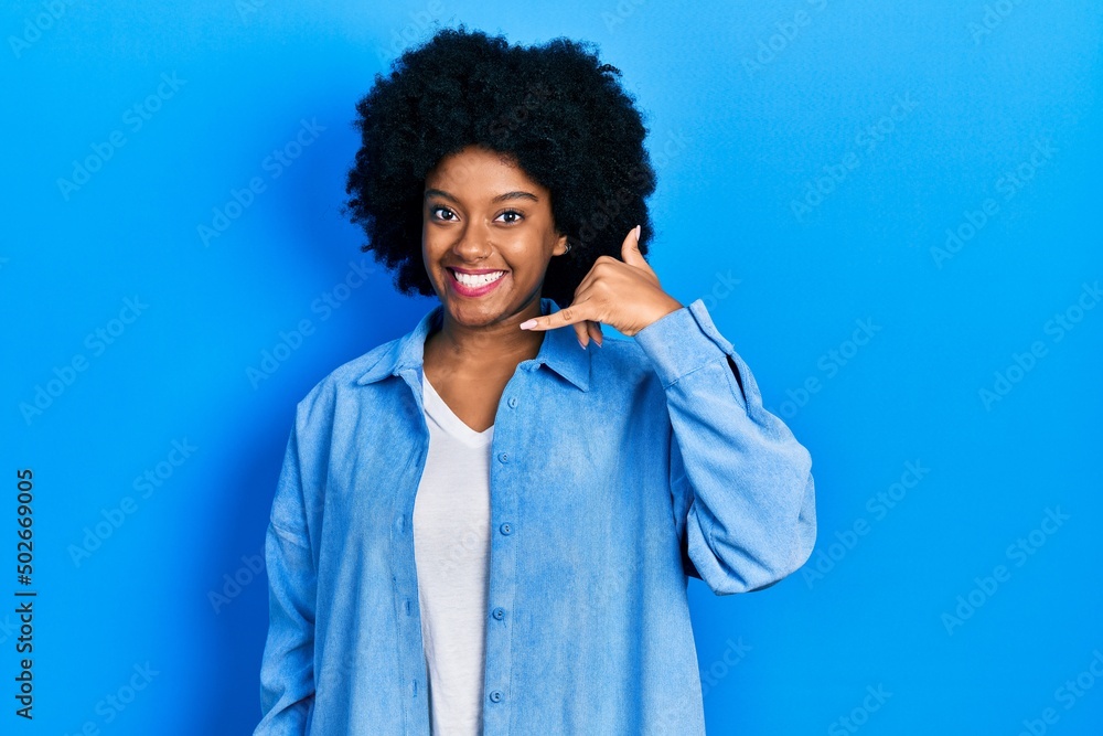 Young african american woman wearing casual clothes smiling doing phone gesture with hand and fingers like talking on the telephone. communicating concepts.