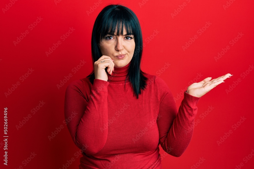 Young hispanic woman presenting with open palms, holding something skeptic and nervous, frowning upset because of problem. negative person. Young hispanic woman presenting with open palms, holding something skeptic and nervous, frowning upset because of problem. negative person.