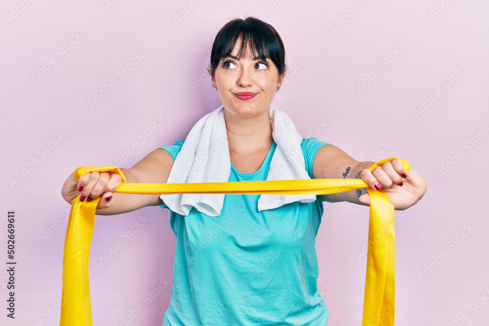 Young hispanic woman wearing sportswear and arm band smiling looking to the side and staring away thinking. Young hispanic woman wearing sportswear and arm band smiling looking to the side and staring away thinking.