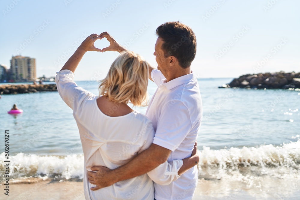 Middle age man and woman couple doing heart symbol with hands at seaside Middle age man and woman couple doing heart symbol with hands at seaside