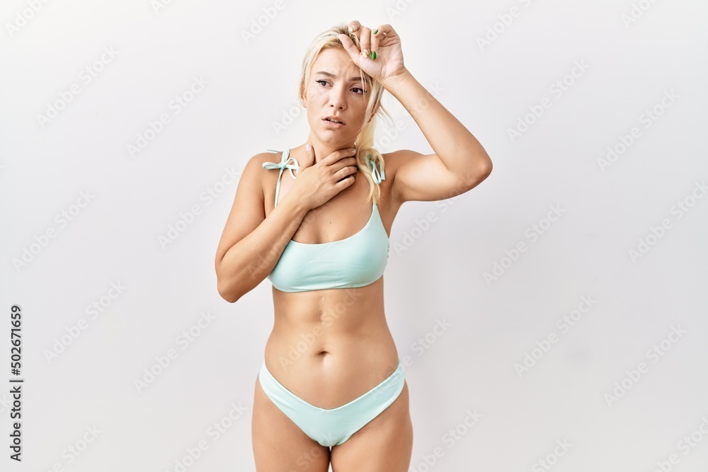 Young caucasian woman wearing bikini over isolated background touching forehead for illness and fever, flu and cold, virus sick Young caucasian woman wearing bikini over isolated background touching forehead for illness and fever, flu and cold, virus sick