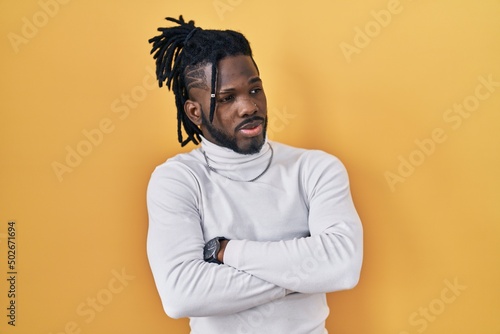 Valokuva African man with dreadlocks wearing turtleneck sweater over yellow background lo