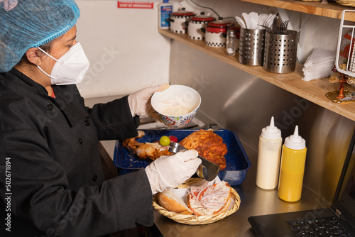 latin woman preparing fast food wearing a mask, cap and gloves