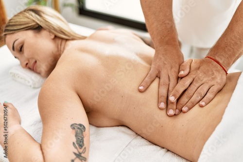 Young caucasian woman at physiotherapy clinic getting muscle massage by professional therapist. Physiotherapist man doing rehabilitation treatment to client