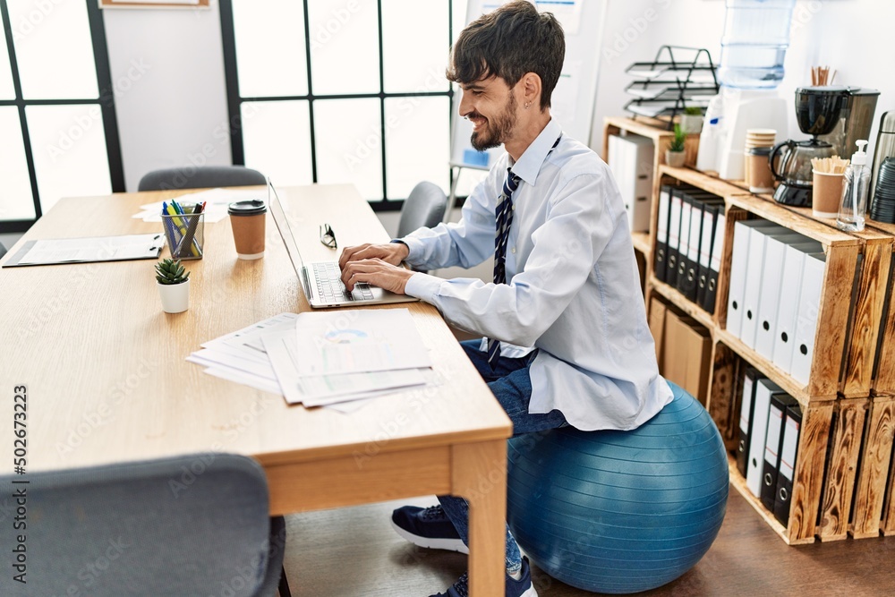 Young hispanic businessman sitting on fit ball working at the office. Young hispanic businessman sitting on fit ball working at the office.