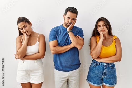 Group of young hispanic people standing over isolated background thinking looking tired and bored with depression problems with crossed arms.