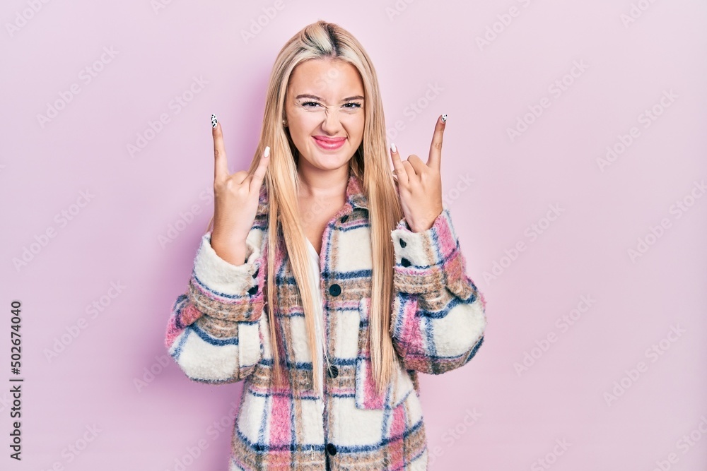 Young blonde girl wearing casual clothes shouting with crazy expression doing rock symbol with hands up. music star. heavy concept. Young blonde girl wearing casual clothes shouting with crazy expression doing rock symbol with hands up. music star. heavy concept.