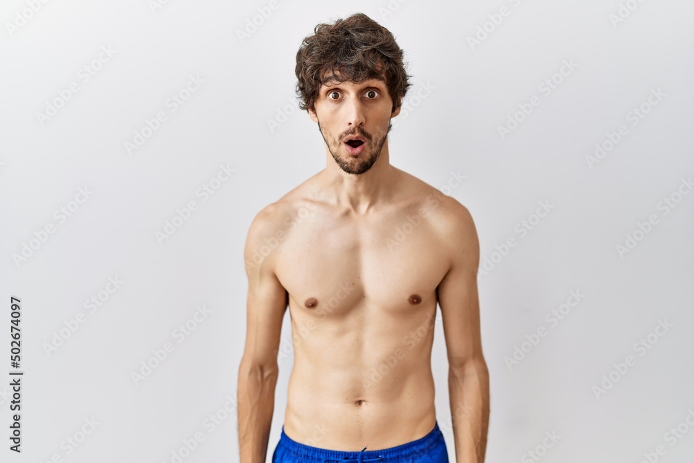 Fototapeta premium Young hispanic man standing shirtless over isolated, background afraid and shocked with surprise expression, fear and excited face.