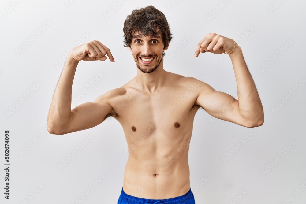 Young hispanic man standing shirtless over isolated, background looking confident with smile on face, pointing oneself with fingers proud and happy.