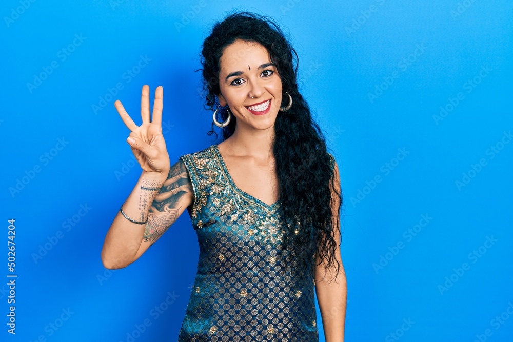 Young woman wearing bindi and traditional kurta dress showing and pointing up with fingers number three while smiling confident and happy. Young woman wearing bindi and traditional kurta dress showing and pointing up with fingers number three while smiling confident and happy.
