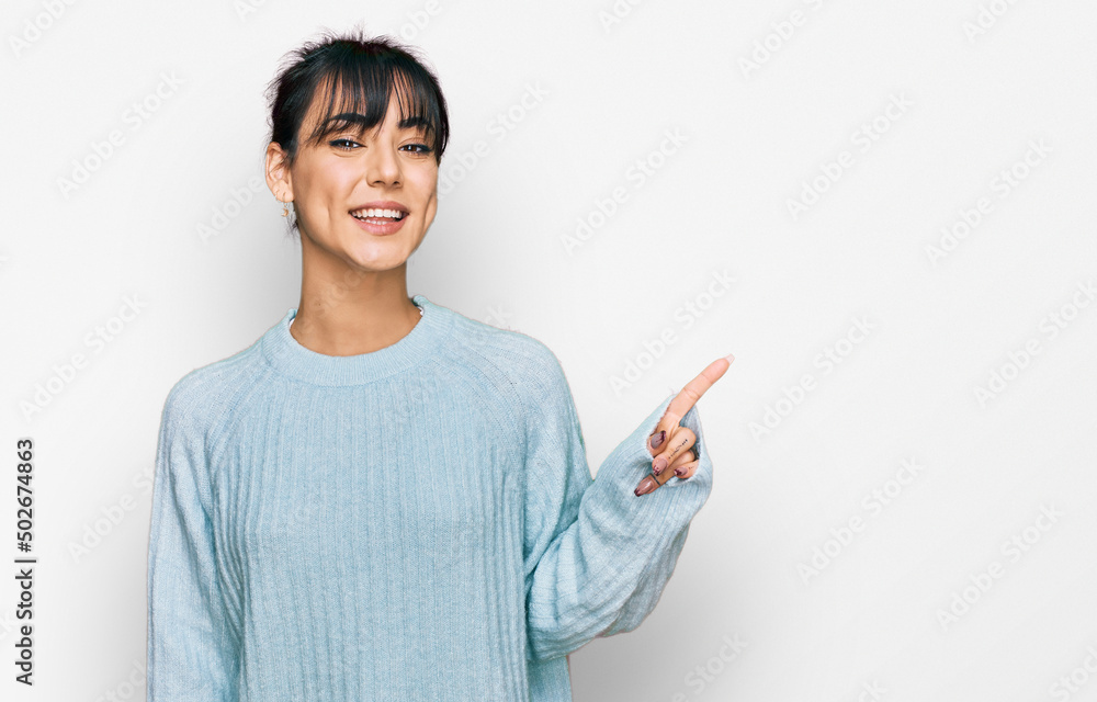 Young hispanic woman wearing casual clothes with a big smile on face, pointing with hand finger to the side looking at the camera. Young hispanic woman wearing casual clothes with a big smile on face, pointing with hand finger to the side looking at the camera.