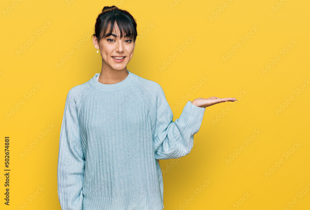 Young hispanic woman wearing casual clothes smiling cheerful presenting and pointing with palm of hand looking at the camera. Young hispanic woman wearing casual clothes smiling cheerful presenting and pointing with palm of hand looking at the camera.
