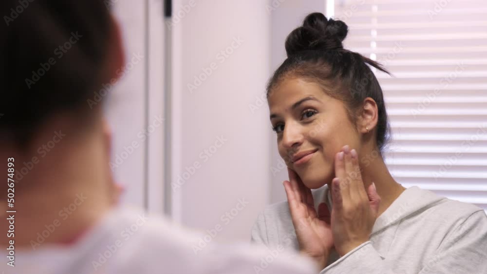 Beautiful young hispanic woman happily rubs face during routine skin care Beautiful young hispanic woman happily rubs face during routine skin care