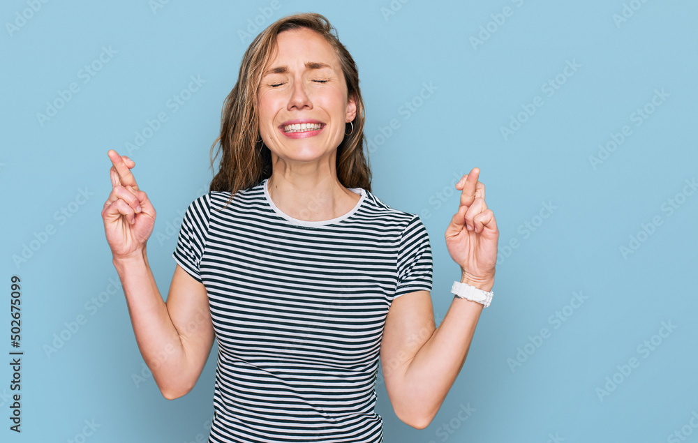 Young blonde woman wearing casual clothes gesturing finger crossed smiling with hope and eyes closed. luck and superstitious concept. Young blonde woman wearing casual clothes gesturing finger crossed smiling with hope and eyes closed. luck and superstitious concept.