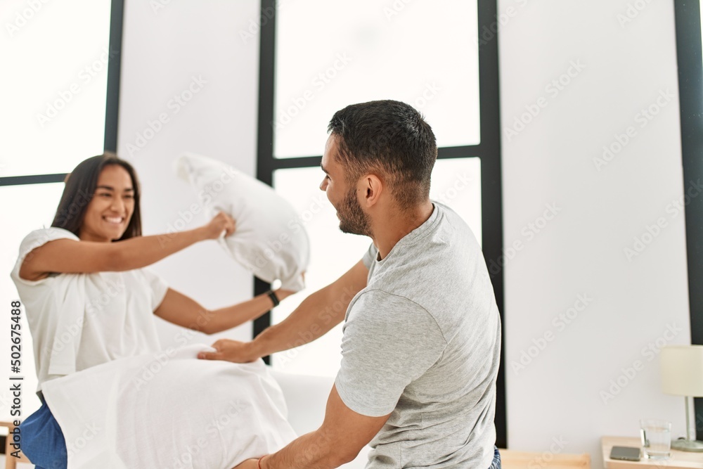 Young latin couple smiling happy fighting with pillows on the bed at home. Young latin couple smiling happy fighting with pillows on the bed at home.