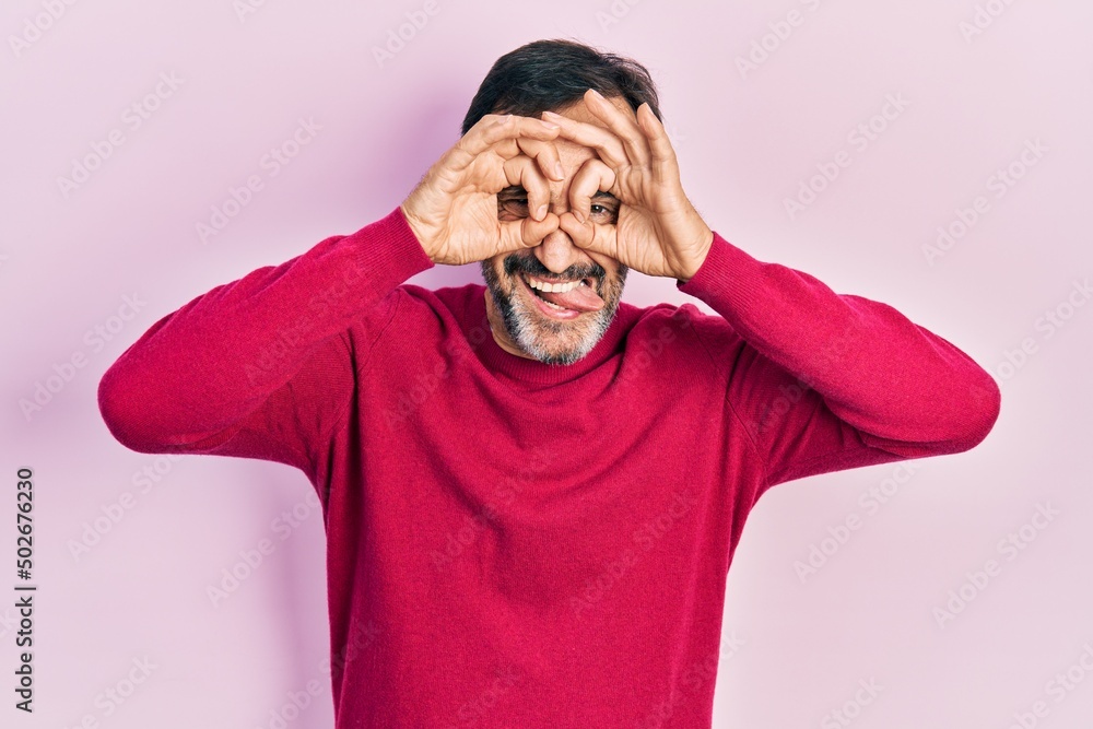 Middle age hispanic man wearing casual clothes doing ok gesture like binoculars sticking tongue out, eyes looking through fingers. crazy expression. Middle age hispanic man wearing casual clothes doing ok gesture like binoculars sticking tongue out, eyes looking through fingers. crazy expression.