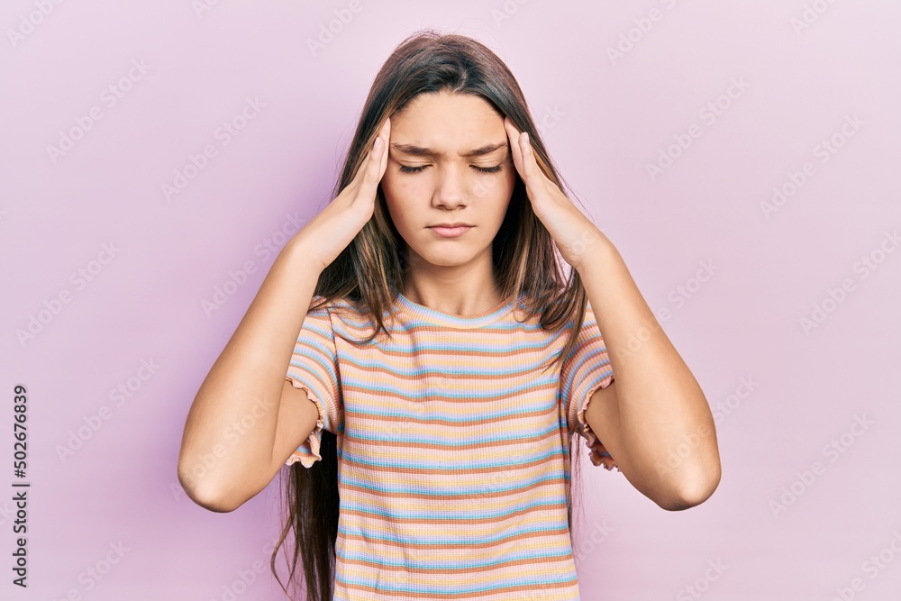 Young brunette girl wearing casual striped t shirt with hand on head, headache because stress. suffering migraine. Young brunette girl wearing casual striped t shirt with hand on head, headache because stress. suffering migraine.