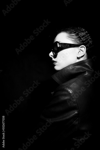 woman in leather coat and sunglasses, black background