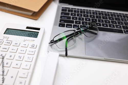 Office and business background, office table desk workspace with blank notebook, calculator, laptop and glasses
