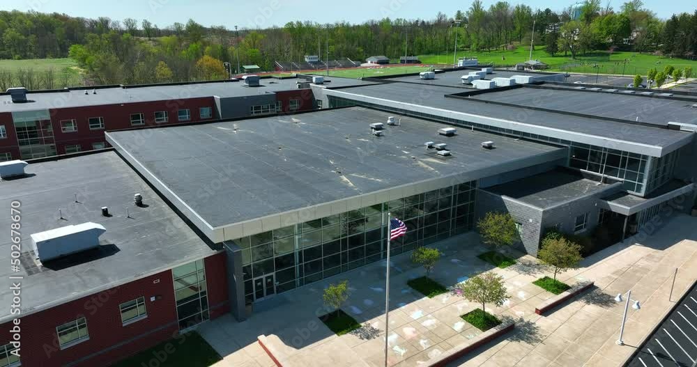 School building in USA. American flag pole and front entrance of modern public education facility. Aerial view. School building in USA. American flag pole and front entrance of modern public education facility. Aerial view.