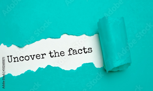 Text sign showing Uncover the facts on the blue torn paper photo