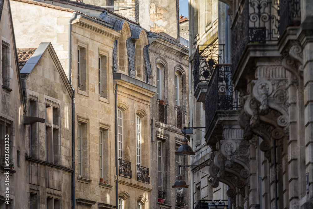 Facade of medieval buildings in a dark street, narrow, in the city center of Bordeaux, France. These buildings are typical of the Southwestern French architecture.....