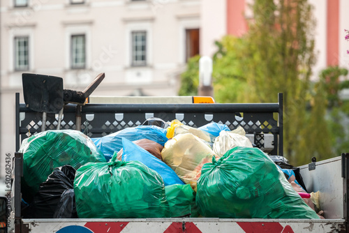 Garbage truck full of garbage bags, overflowing, contaning urban litter and dump, ready to be sent to a waste collection center in Europe...