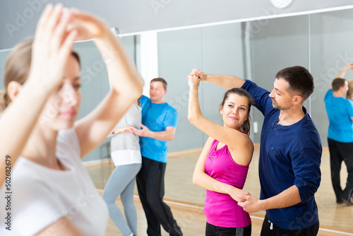 Young dancing couple enjoying active dance during group class in modern studio