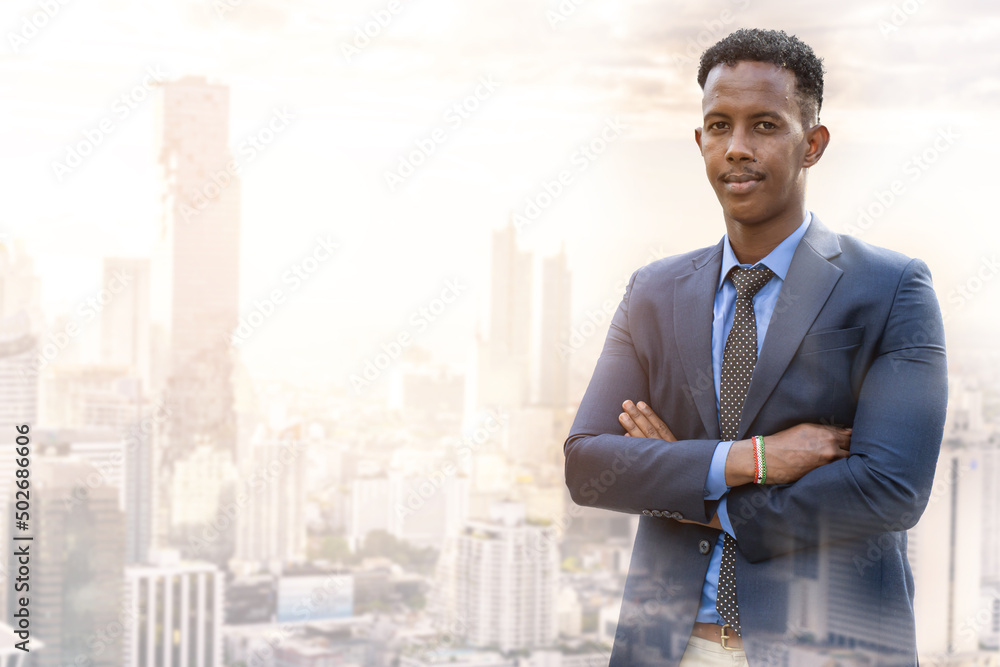 Business people in city. Portrait of an handsome businessman. Modern businessman. Confident young man in full suit and glasses while standing outdoors looking away with cityscape in the background