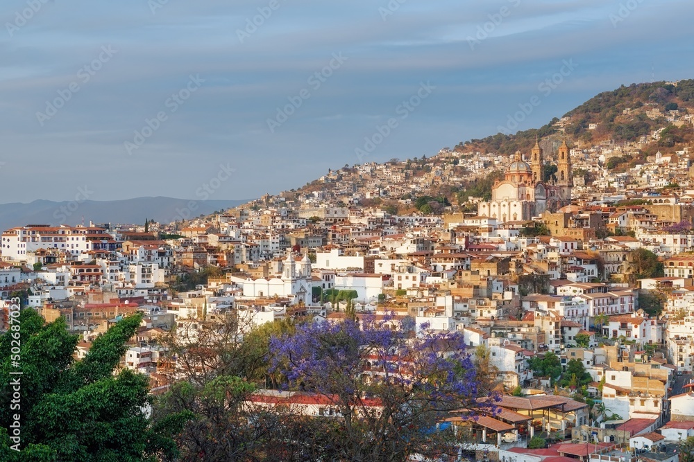 Colonial city on a mountainside before sunset. The architecture is illuminated by the rays of the sun. Evening sky. The cramped streets of Taxco in Mexico