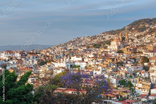 Colonial city on a mountainside before sunset. The architecture is illuminated by the rays of the sun. Evening sky. The cramped streets of Taxco in Mexico © Vladimir Lyakishev