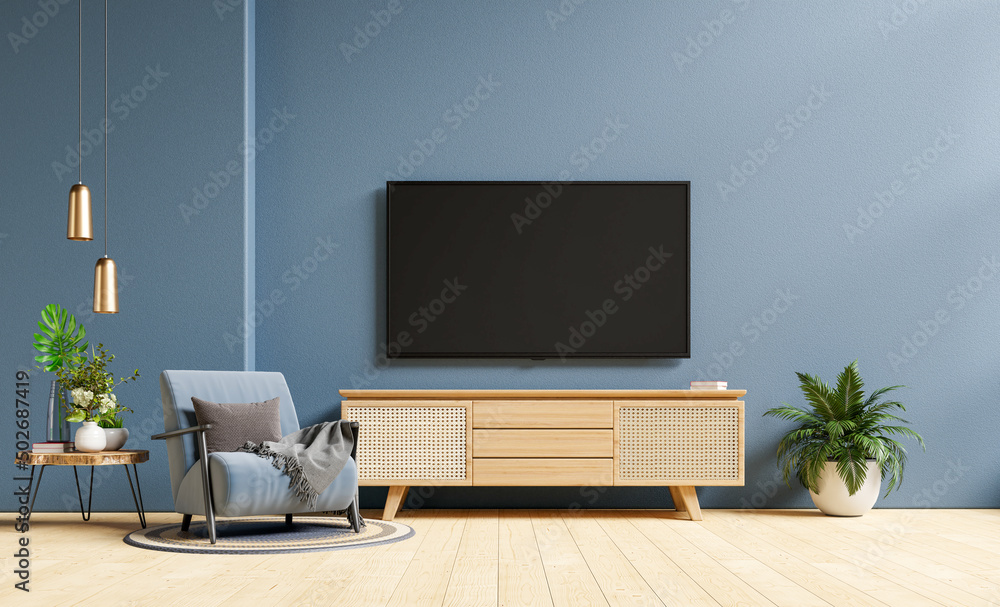 Fototapeta premium TV and Cabinet in modern living room with armchair on dark blue concrete wall background.