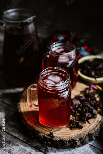 Agua de Jamaica or roselle mocktail drink, summer beverage in mexico with ice and dry hibiscus petals on table background