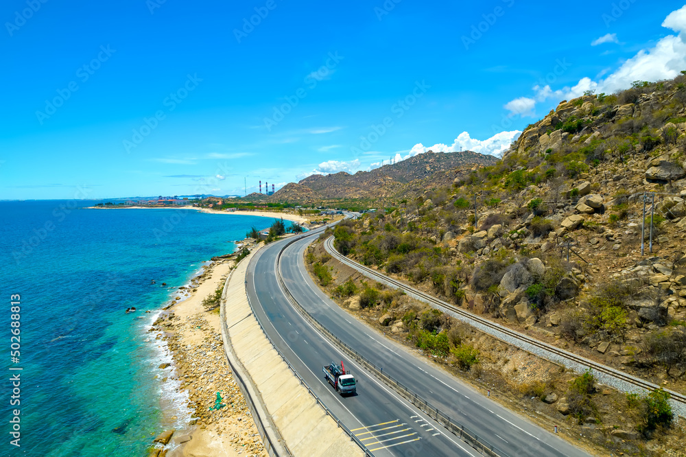 The coastal road in Ca Na bay, Binh Thuan seen from above with the boulevard and railway, the coast close together is considered a beautiful bay in central Vietnam. The coastal road in Ca Na bay, Binh Thuan seen from above with the boulevard and railway, the coast close together is considered a beautiful bay in central Vietnam.