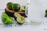 Jar glass of lemonade drink with green lemons or lime on a white background in Latin America