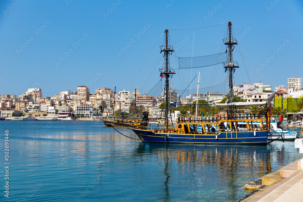 View of vintage wooden sailboats moored in harbor of coastal tourist city of Sarande on Ionian Sea in Albania on sunny spring day..