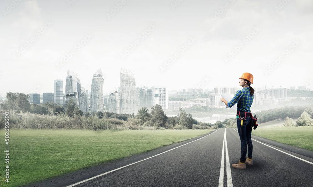 Woman in safety helmet standing on road Woman in safety helmet standing on road