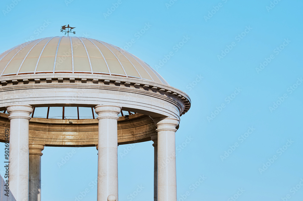 Granite columns of the rotunda support a dome with a transparent roof. Sun glare on the surface of natural stone. It's evening. Granite columns of the rotunda support a dome with a transparent roof. Sun glare on the surface of natural stone. It's evening.