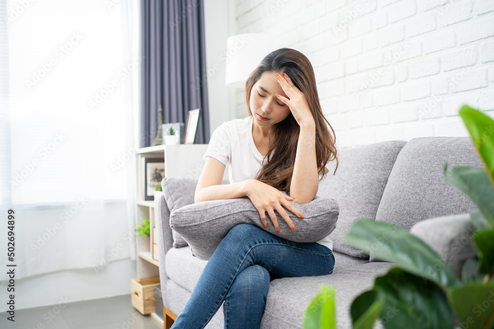 Young Asian women on sofa closing her eyes are suffering from headache Young Asian women on sofa closing her eyes are suffering from headache