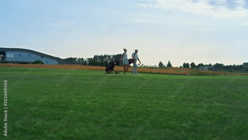 Golf couple walking course outdoors. Sport people examine country club fairway. Golf couple walking course outdoors. Sport people examine country club fairway.