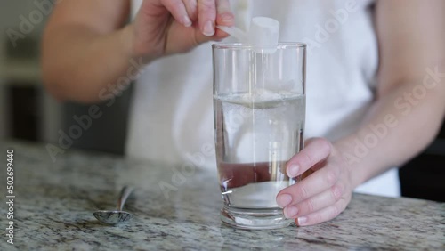 Energy drink powder is poured into clear glass and stirred, turning yellow