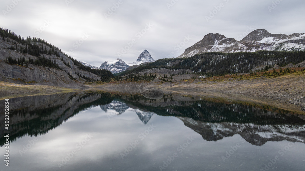 Prominent mountain reflecting in alpine lake during overcast day, Pano, Mt Assiniboine PP, Canada